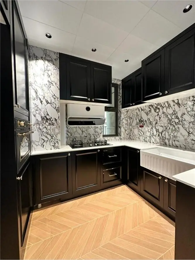 Black raised-panel kitchen with marble splashback